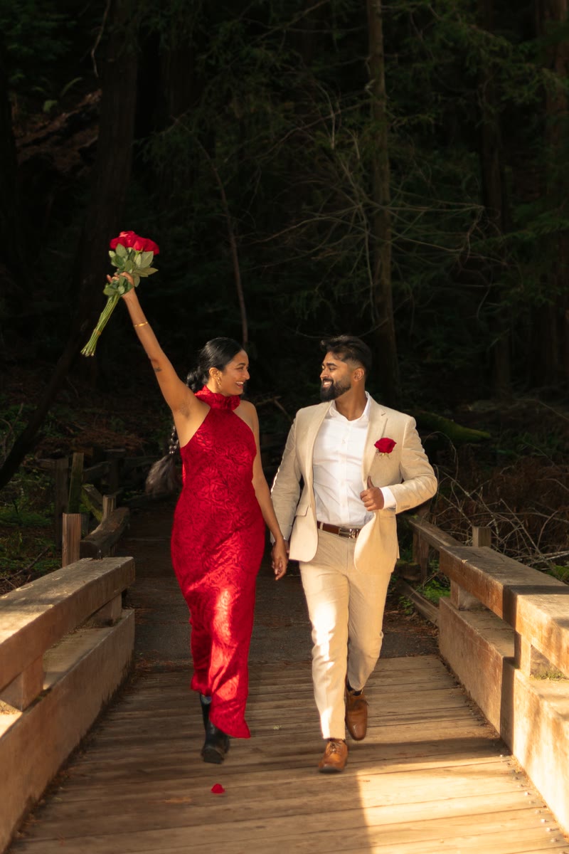 Nish and Pooja on a wooden bridge, Pooja holding roses